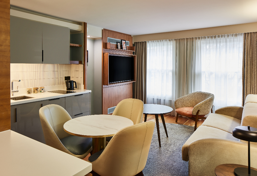Stylish living room and kitchen space at master Farringdon London serviced apartments, with dining table, modern kitchenette, and large windows bringing in natural light.