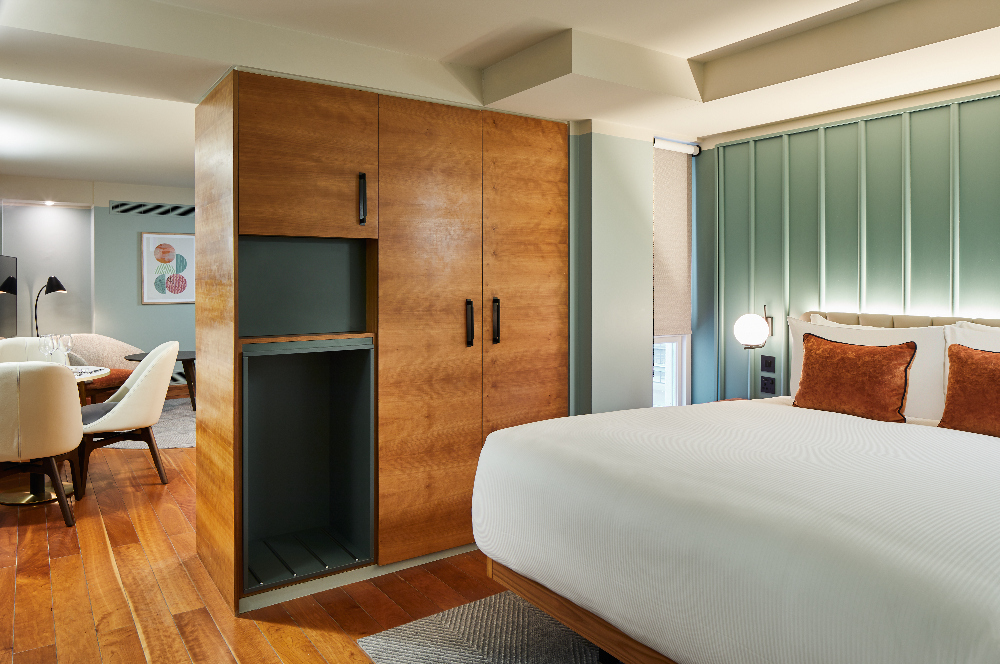 Overview of the one bedroom open plan suite at master Farringdon London serviced apartments, blending bedroom, living, and kitchen spaces with stylish decor and wooden accents.