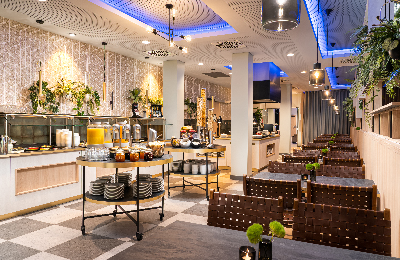 A buffet station with juice dispensers, cereal dispensers, and woven-leather chairs.