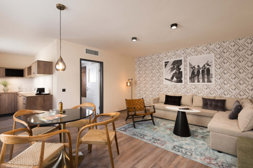 Spacious one-bedroom apartment at master Linzergasse with open-plan living area, modern kitchenette, dining table, and cozy seating with patterned feature wall.