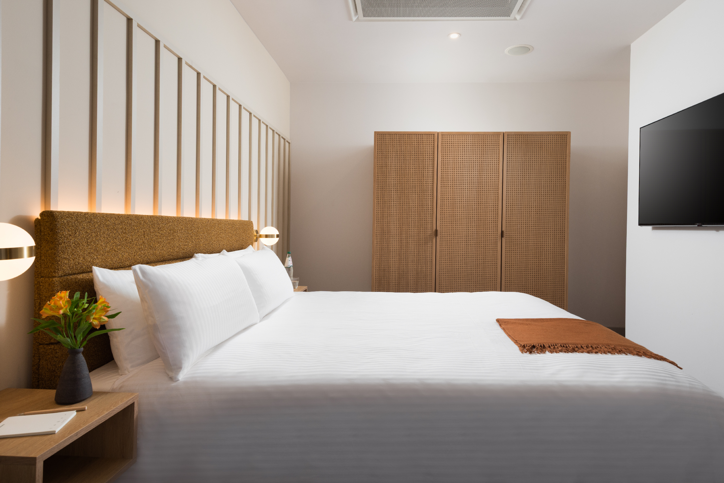 Family Apartment bedroom at master Wola Warsaw, featuring a comfortable double bed, upholstered headboard, warm lighting, and modern minimalist design.