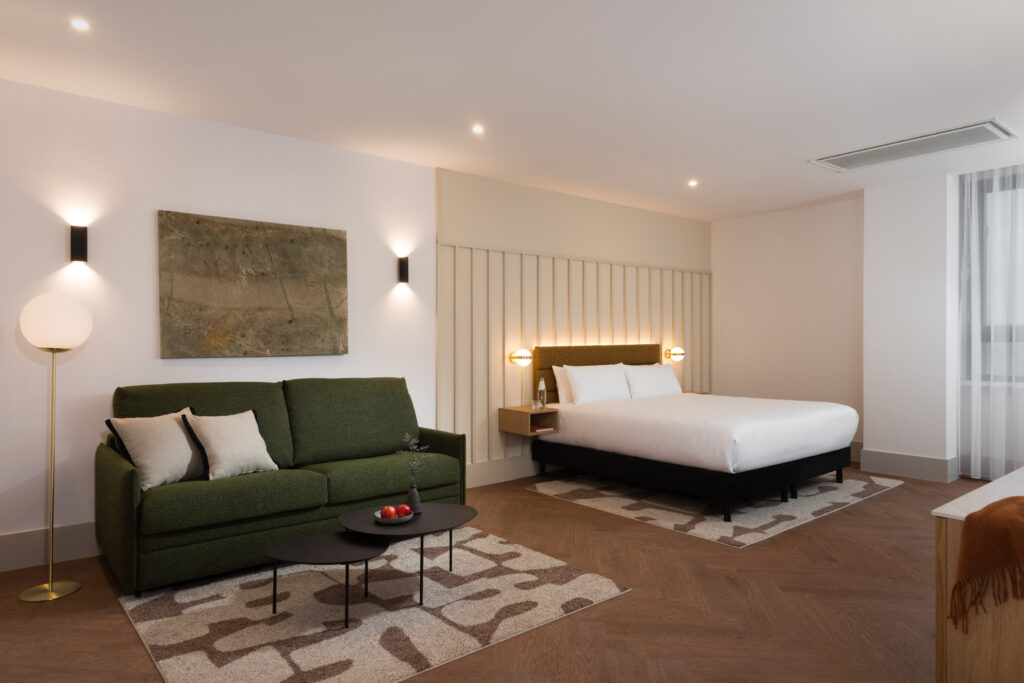 Spacious studio apartment at master Wola Serviced Apartments with double bed, green sofa, and seating area