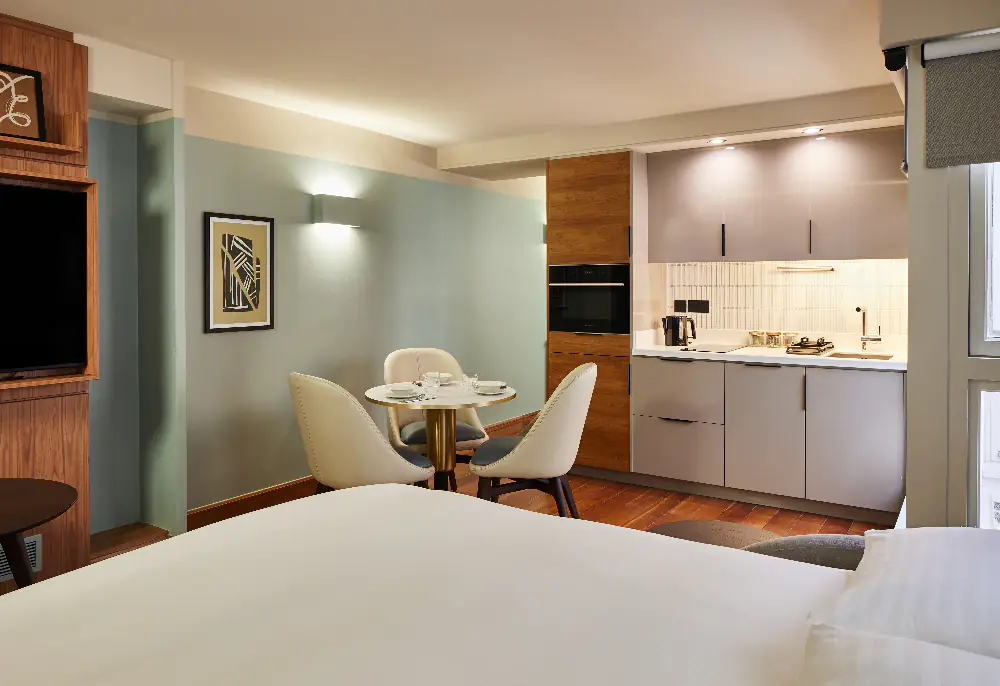 Inviting lounge space at master Farringdon London serviced apartments, with comfortable sofa, coffee table, and view of the compact modern kitchen.