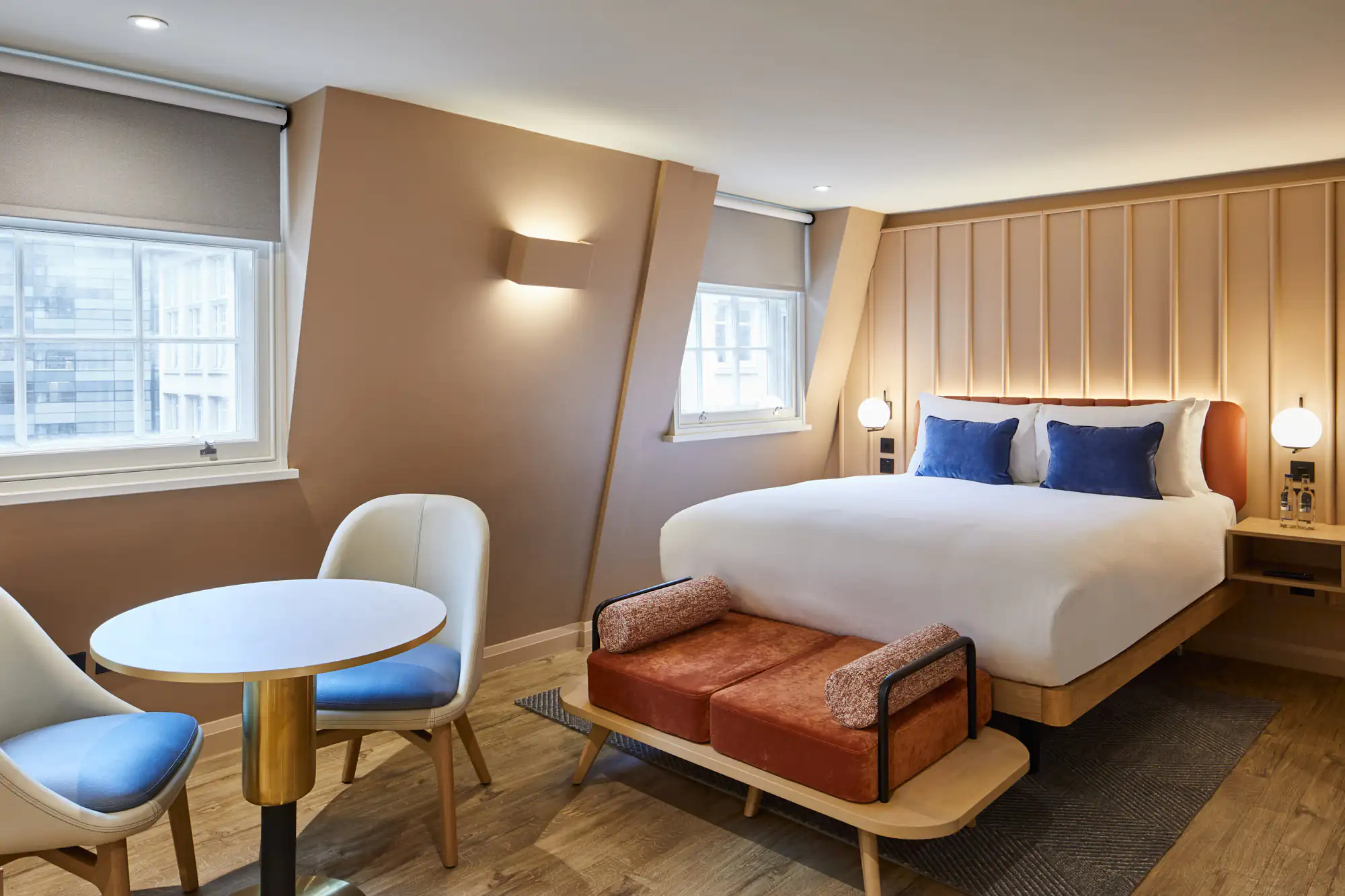 Contemporary studio interior at master Cannon London showcasing a plush bed, dining table with chairs, and minimalist decor in warm earthy tones."