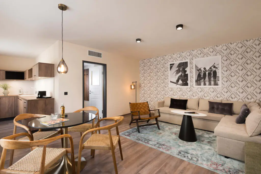 Spacious one-bedroom apartment at master Linzergasse with open-plan living area, modern kitchenette, dining table, and cozy seating with patterned feature wall.