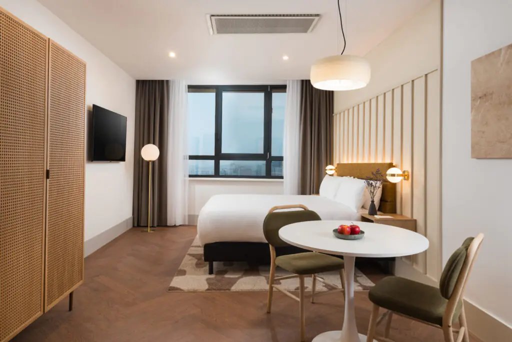 Studio apartment bedroom and dining area at master Wola Serviced Apartments with double bed, round table, and city view window