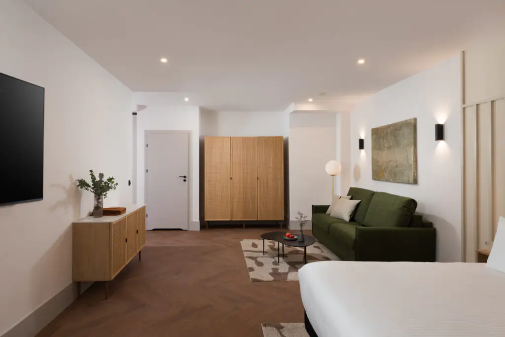 Studio apartment living space at master Wola Serviced Apartments with sofa, wardrobe, and warm lighting